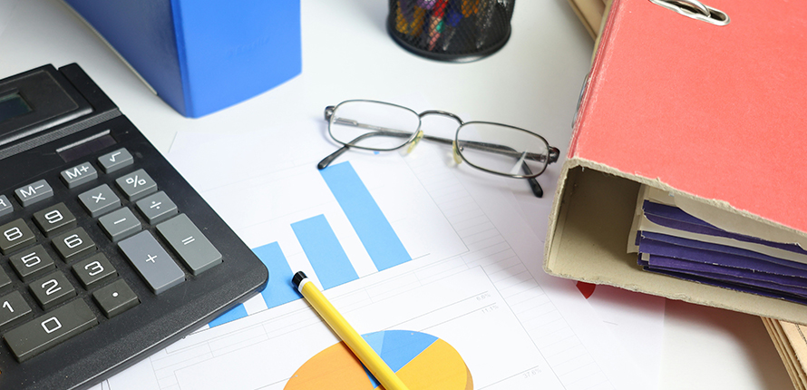 A report with two graphs, documentation in binders and a calculator on a desk